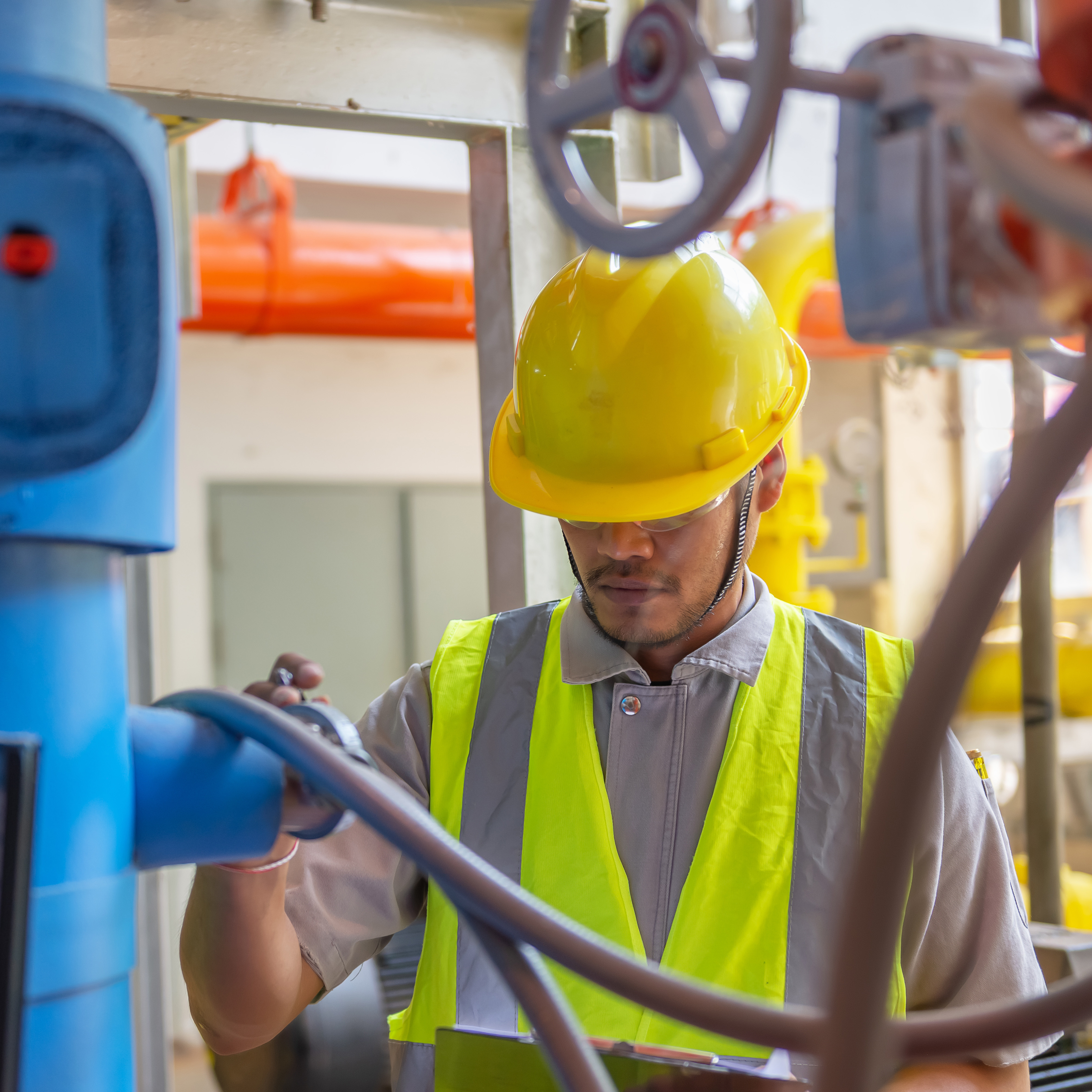 Asian engineer wearing glasses working in the boiler room,maintenance checking technical data of heating system equipment,Thailand people